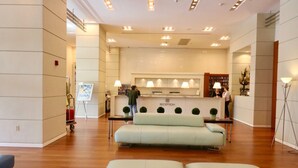 A reception area with a reception desk, a sofa, and a floor lamp. - Connecting Rooms-Coconut Grove 10th Floor- Parking Included (Miami)