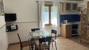 Une cuisine compacte avec un coin repas, un téléviseur et une fenêtre avec des rideaux.