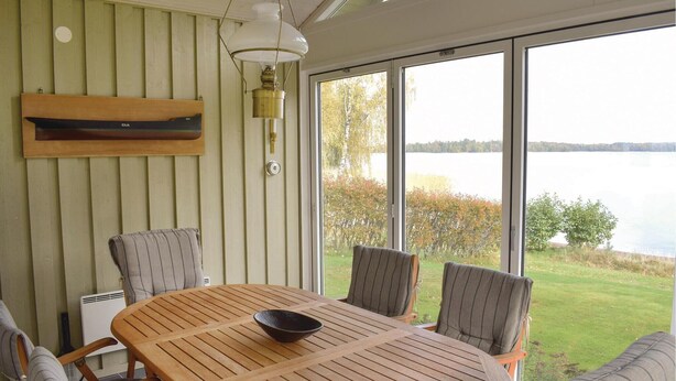 Una mesa de madera con cuatro sillas, un tazón y una estantería de pared con una lámpara.