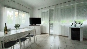 A modern kitchen with a dining table, chairs, a TV, and a potted plant. - Ferienhaus mit Pool und Internet (Balatonmáriafürdő)