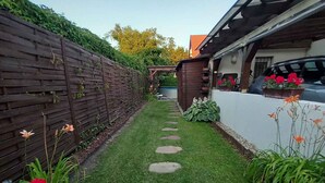A paved patio with a wheelbarrow, a wooden fence, and potted plants. - Ferienhaus mit Pool und Internet (Balatonmáriafürdő)