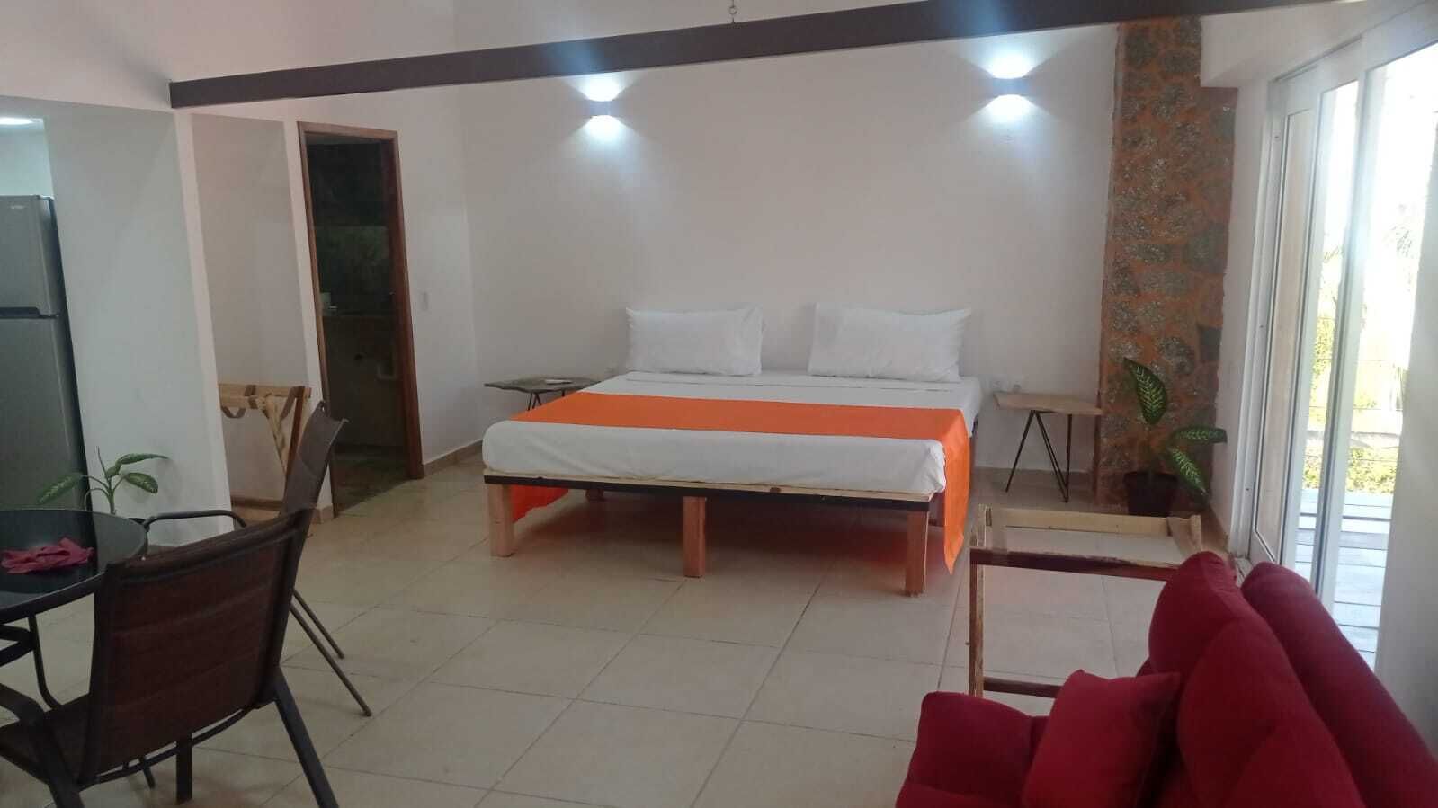 A bedroom with a bed, a desk, and chairs.