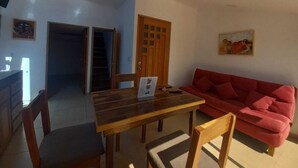 En matplats med ett träbord och stolar, en röd soffa och en trappa som leder till ett annat rum.