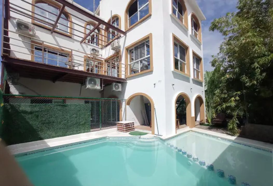 En moderne bygning med swimmingpool, store vinduer og en balkon.