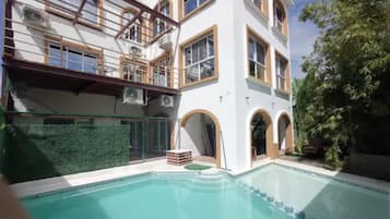 En moderne bygning med swimmingpool, store vinduer og en balkon.