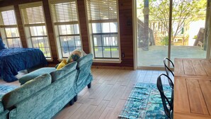 A room with a bed, a sofa, a table, and a large window with blinds. - Trinity Chalet, Lakefront  Downstairs Home w/, Covered Patio! Sleeps 3 (Trinity)