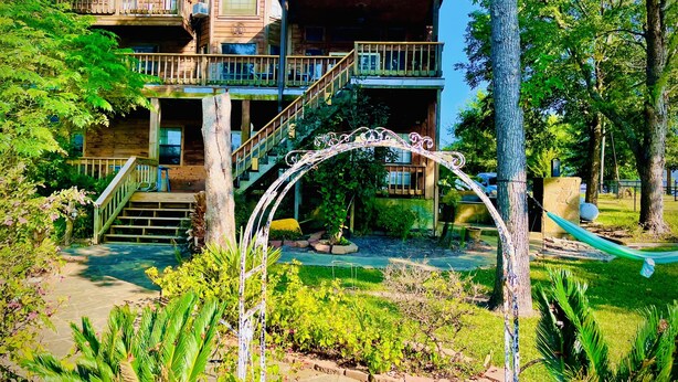 A wooden cabin with a balcony, a staircase, and a hammock. - Trinity Chalet, Lakefront  Downstairs Home w/, Covered Patio! Sleeps 3 (Trinity)