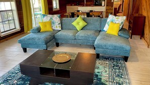 A cozy living room with a blue sectional sofa, a dark coffee table, and a patterned rug. - Trinity Chalet, Lakefront  Downstairs Home w/, Covered Patio! Sleeps 3 (Trinity)