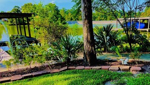 A garden with a pond, a wooden pergola, and a variety of plants. - Trinity Chalet, Lakefront  Downstairs Home w/, Covered Patio! Sleeps 3 (Trinity)