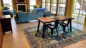 A cozy room with a wooden floor, a sofa set, a dining table with chairs, and a fireplace. - Trinity Chalet, Lakefront  Downstairs Home w/, Covered Patio! Sleeps 3 (Trinity)