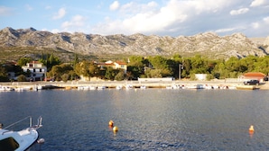 A marina with boats docked, a white boat in the foreground, and mountains in the background.