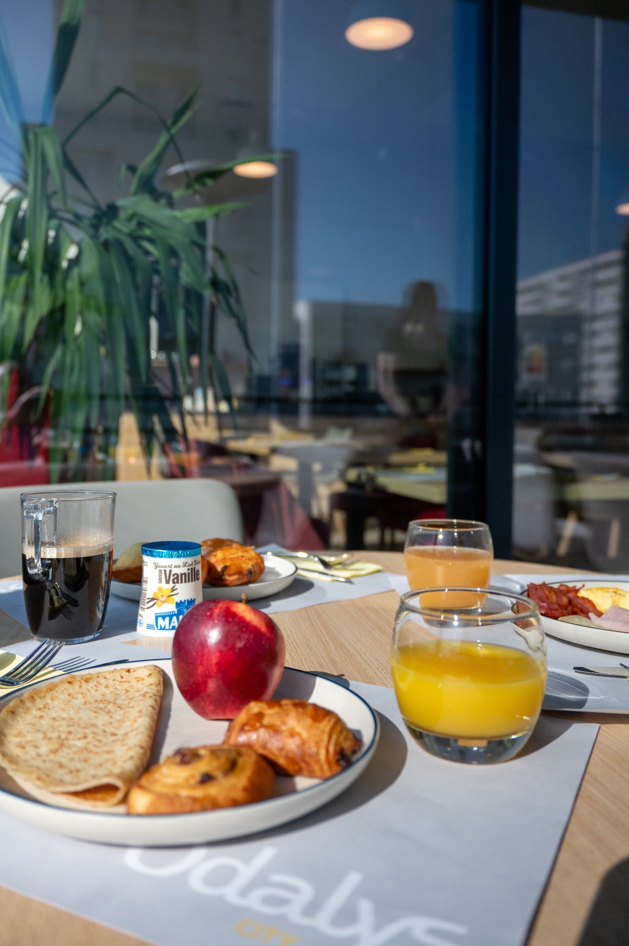 Et morgenbord med croissant, æble, juice og en kop kaffe.