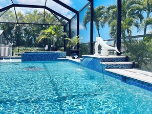 Ein Swimmingpool mit klarem, blauem Wasser, umgeben von einer Glaskonstruktion, und eine weiße Skulptur am Rand.
