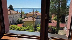 A view from a window overlooking a coastal area with terraced houses and a clear blue sky.