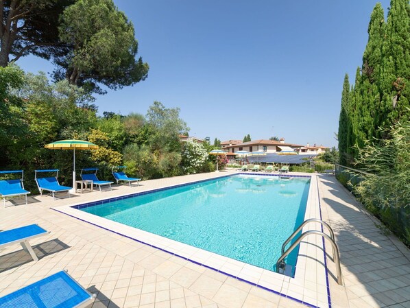 A swimming pool with blue lounge chairs and umbrellas, surrounded by greenery and a building in the background. - Stunning  villa with WIFI, A/C, private pool, hot tub, TV, terrace, pets allowed and panoramic v... (Montelupo Fiorentino)