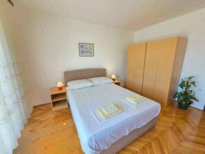 Une chambre à coucher avec un lit, des lampes de chevet, une armoire et une plante en pot.