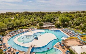 A large outdoor swimming pool with multiple lanes, surrounded by beach umbrellas and lounge chairs.