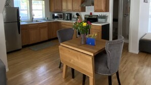 Eine moderne Küche mit Holzschränken, einem Esstisch mit Stühlen und einem Kühlschrank.
