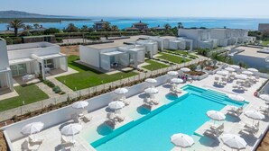 Un moderno resort con una piscina grande, asientos al aire libre y vistas al mar.