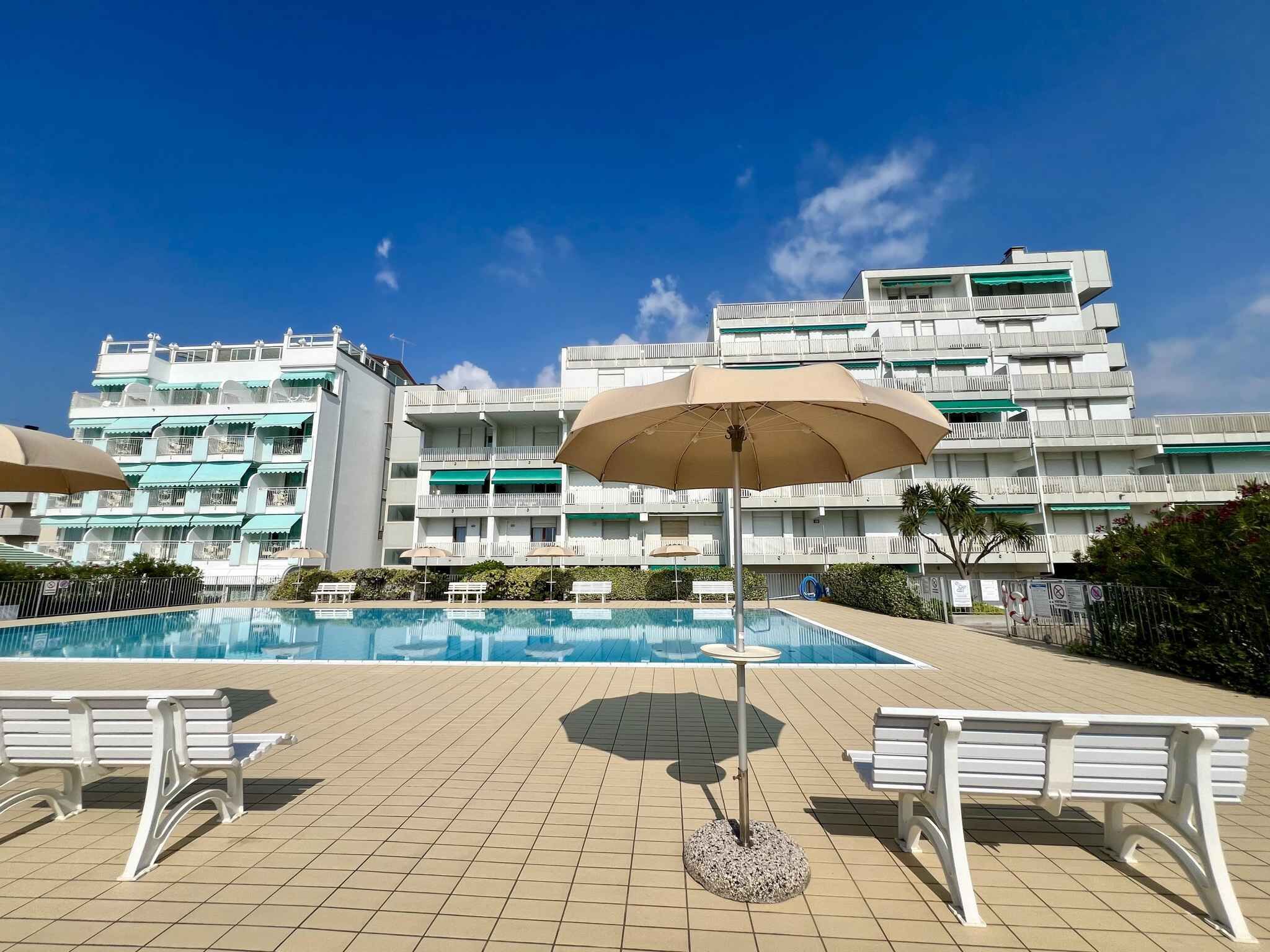 Et hotel med swimmingpool, udendørs siddepladser og en bygning med flere etager og altaner.