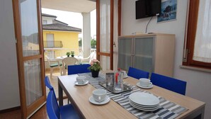 Un coin repas avec une table dressée pour quatre personnes, un buffet et un téléviseur fixé au mur.