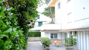 A courtyard with a stone floor, potted plants, and a table with chairs.
