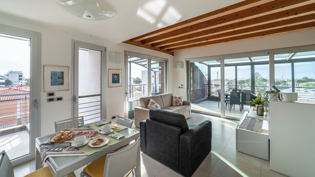 A modern living room with a dining area, large windows, and a view of the city.