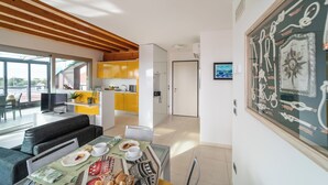 A modern living room with a sofa, dining table, and kitchen area.