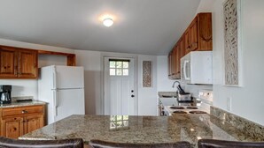 A kitchen with granite countertops, wooden cabinets, a white refrigerator, a microwave, and a stove. - Amazing Town Mountain Getaway (Asheville)