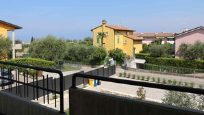 A residential area with yellow and pink buildings, a clear sky, and a road with a metal fence in the foreground.