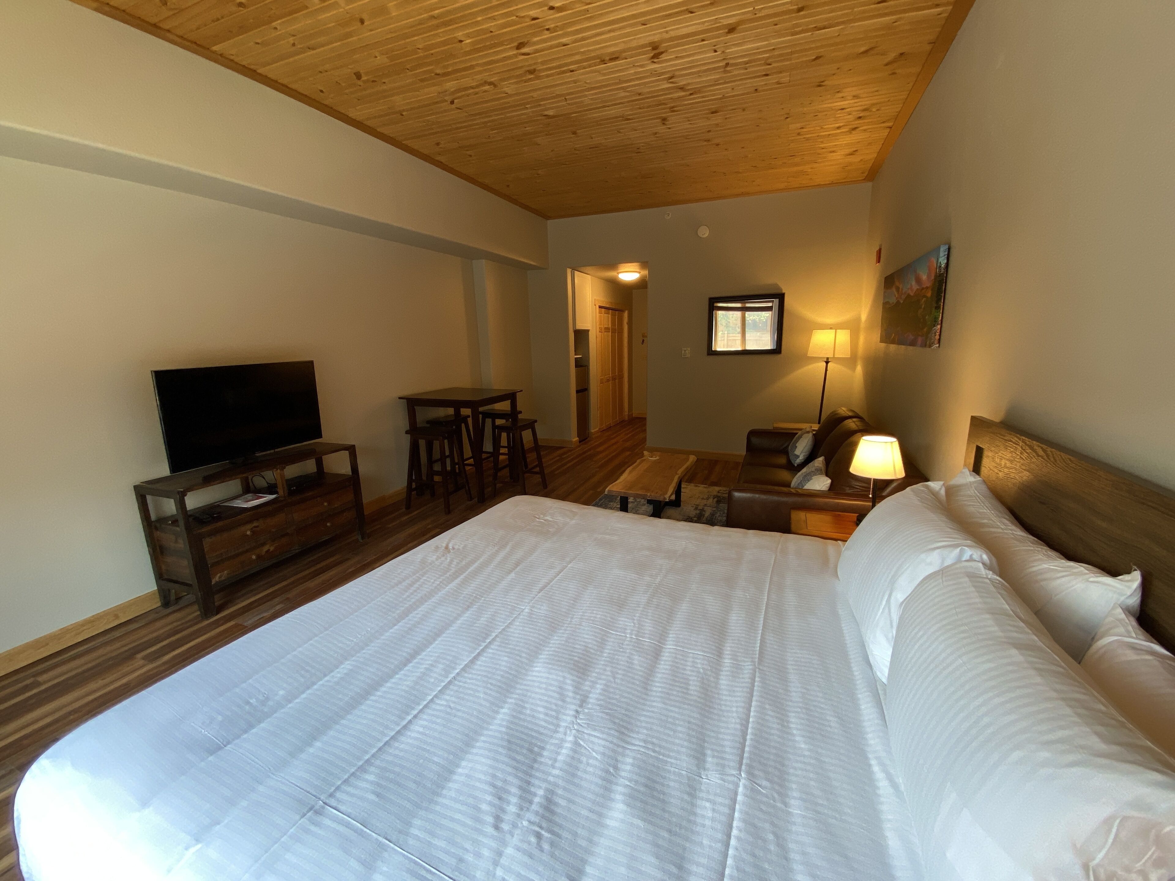 A bedroom with a large bed, a TV, a desk, and a chair.