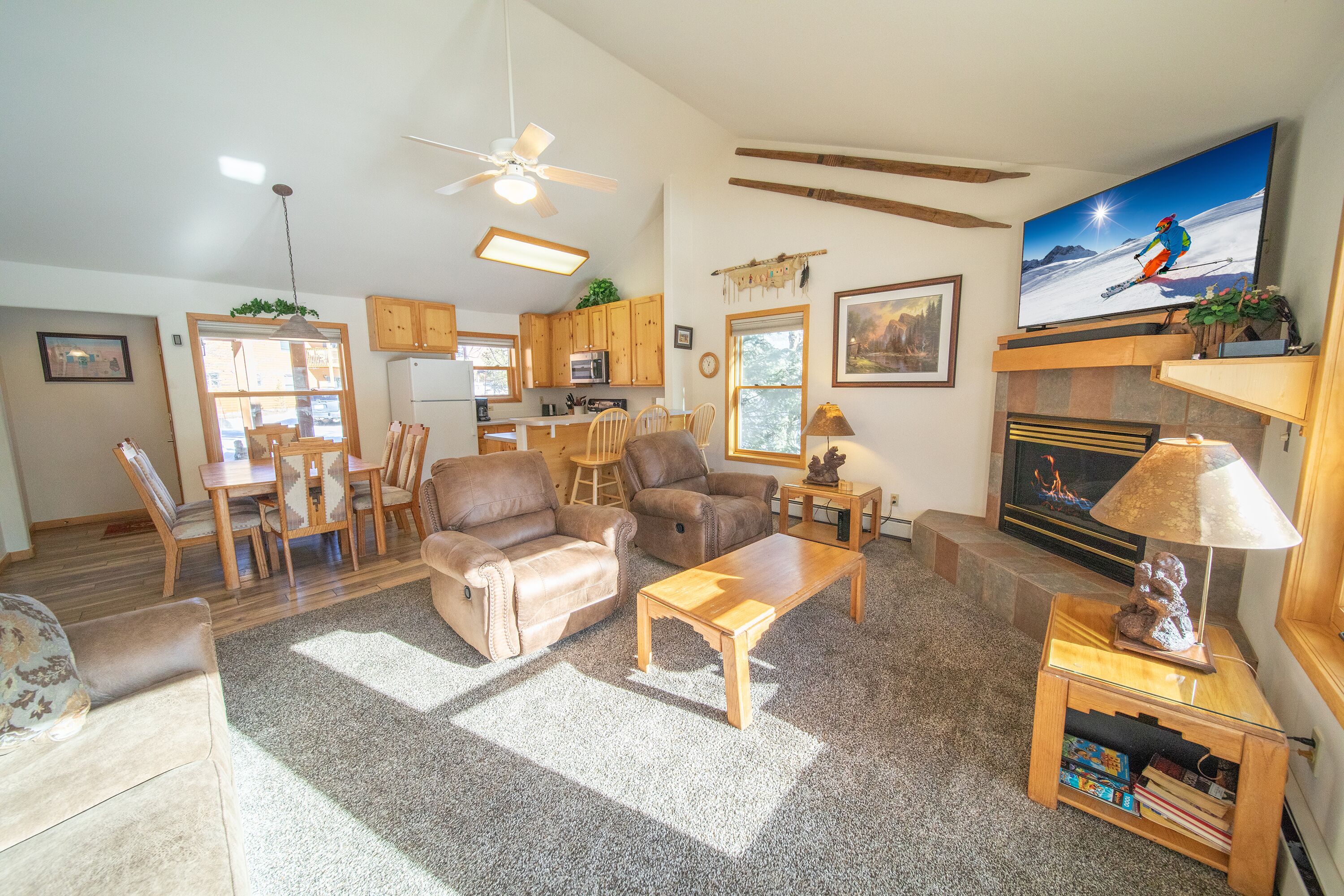 A spacious living room with a fireplace, a television, and a dining area with wooden furniture.