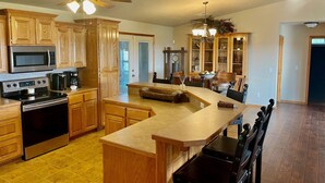 A kitchen with wooden cabinets, a microwave, stove, and a large island with seating.