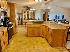 A kitchen with wooden cabinets, a central island, a refrigerator, a microwave, and a coffee maker.