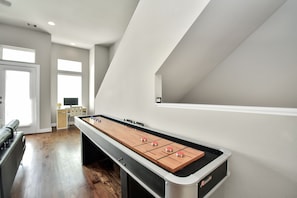 Ein Zimmer mit einem Kicker, einem Schreibtisch mit Computer und einem Fenster.