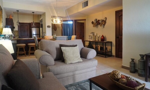 A living room with a grey sofa, a coffee table, and a kitchen area in the background. - Marina Pinacate B-419 Premium Pool View (Puerto Peñasco Centro)
