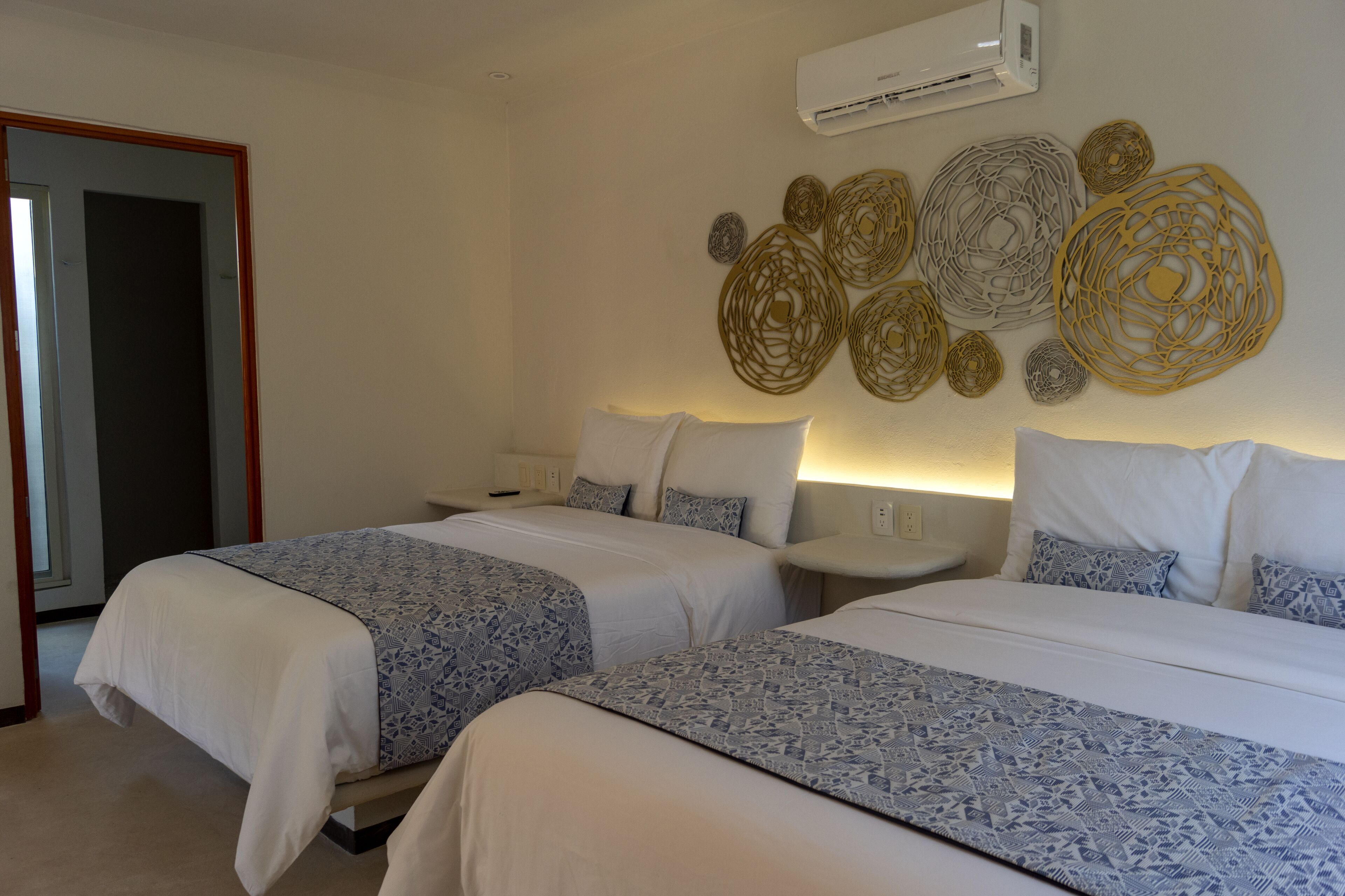 Ein Hotelzimmer mit zwei Betten, einem Nachttisch mit Lampe und dekorativen Wandbildern.