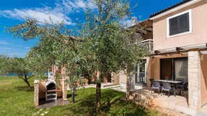 Una casa con patio, mobiliario exterior y vista al mar.