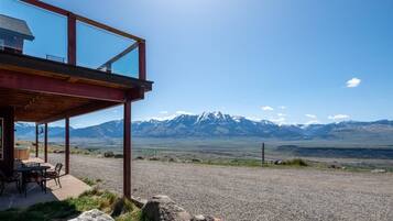 A modern building with a covered patio overlooking a mountainous landscape.