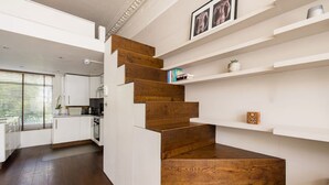 A modern kitchen with white cabinetry, a wooden staircase, and built-in shelves.