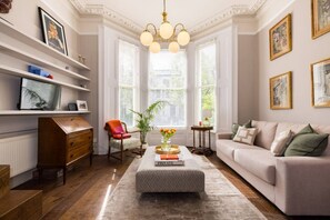 Un salon comprenant un canapé, une table basse, un fauteuil, un bureau et une bibliothèque.