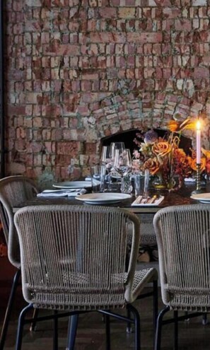 A dining table set with plates, glasses, and a centerpiece with flowers and candles.