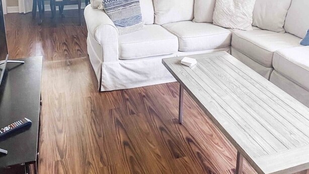 Una sala de estar con un sofá blanco, una mesa de centro y una zona de comedor con una mesa y sillas.