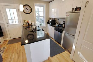 Una cocina moderna con una isla central, electrodomésticos de acero inoxidable y un reloj en la pared.
