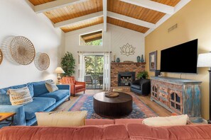 A living room with a blue sofa, a round coffee table, a fireplace, and a television.