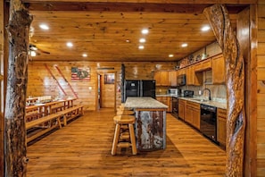 A wooden interior with a kitchen, dining area, and bar stools.