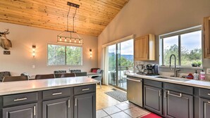 A modern kitchen with dark cabinets, a large island, and a view of the outdoors. - 'Elkwood Lodge' Cabin w/ Hot Tub in Star Valley! (Star Valley)