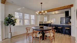 Une cuisine spacieuse avec une table de salle à manger ronde, des chaises en bois et une grande plante en pot.