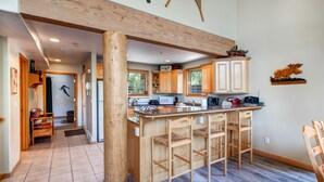 Une cuisine spacieuse avec des meubles en bois, un grand îlot central doté de tabourets de bar et une poutre en bois au plafond.
