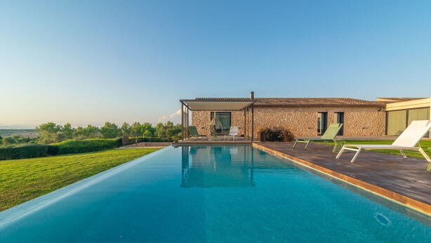 Ein modernes Haus mit Swimmingpool, Sitzgelegenheiten im Freien und Blick auf die Landschaft.